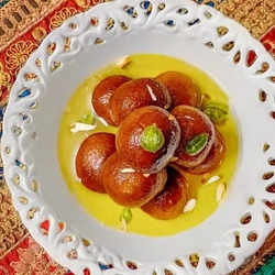 A mouthwatering pile of golden brown Gulab Jamuns glistening in sugar syrup